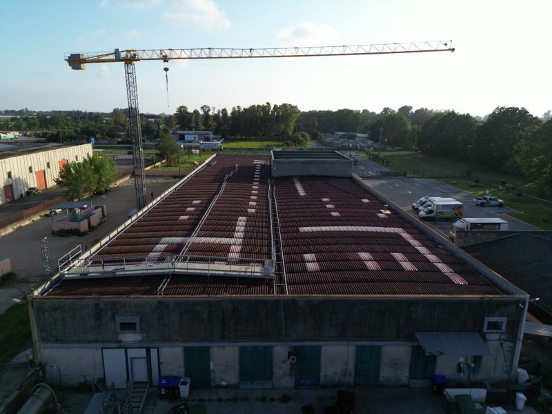 Capannone a Sabaudia prima della rimozione della copertura in amianto: passerella in acciaio con parapetti sulla falda e gru a torre a terra